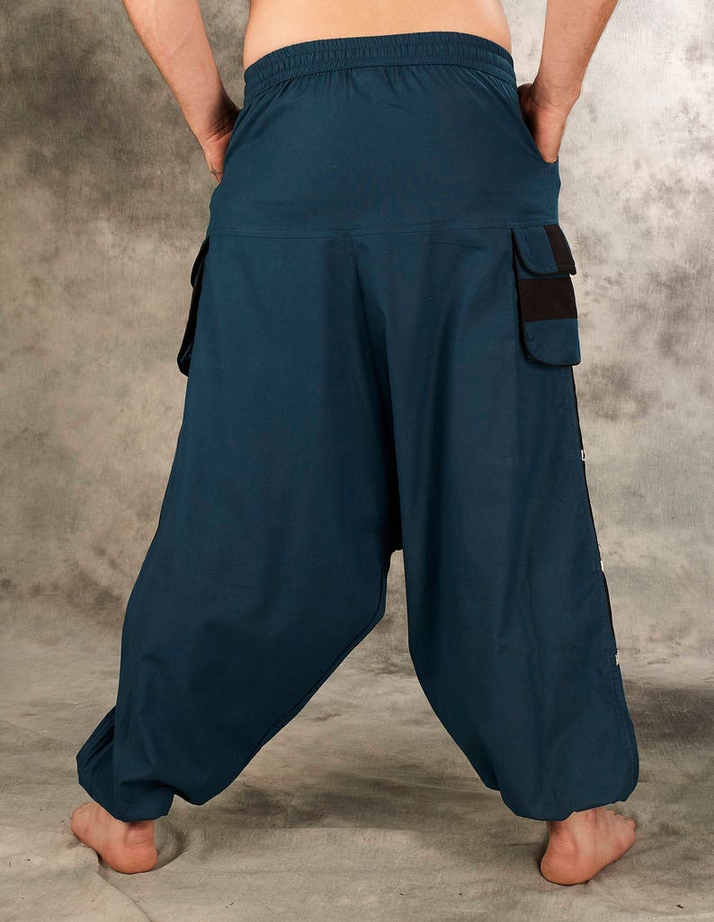 May include: Dark blue, loose-fitting pants with a drawstring waist and multiple pockets. The pants have a black trim and a button detail on the side.