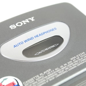 May include: A grey Sony cassette player featuring a silver oval window with the blue text AUTO WIND HEADPHONES and the black text AUTO REVERSE. The device includes the model number WM-EX348, a CE mark, and technical battery information printed in white.