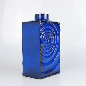 Peut inclure: Un vase en céramique bleu cobalt de forme carrée avec un motif en spirale sur un côté.