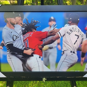 May include: Framed print of a baseball game scene. Players in gray and red uniforms are in a physical altercation. The player in red has the number 11 on his jersey. The player in gray has the number 7 on his jersey.