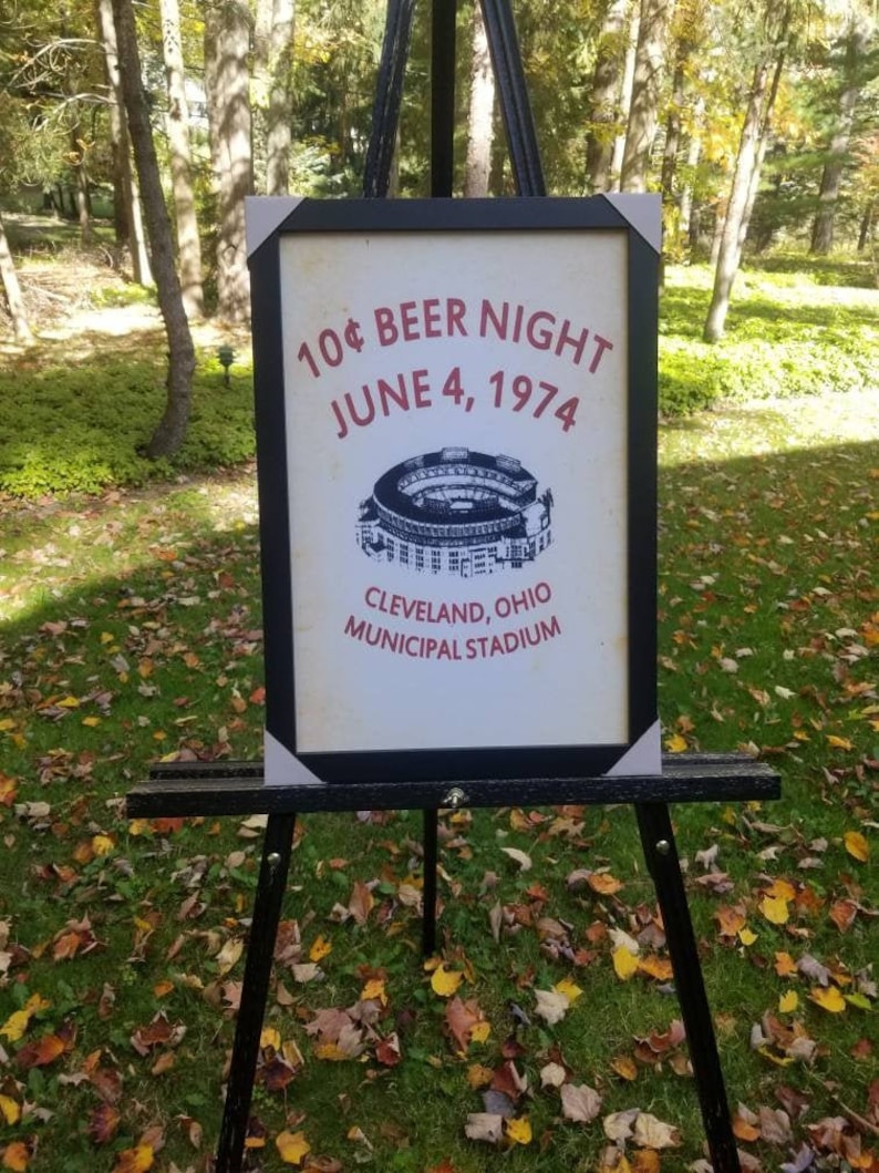 May include: A framed poster advertising a 10&cent; Beer Night at Cleveland, Ohio's Municipal Stadium on June 4, 1974. The poster features a black and white illustration of the stadium.