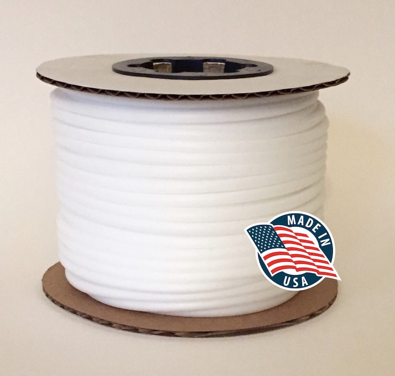 May include: A spool of white elastic cord. The cord is tightly wound around a cardboard core. A sticker with the text "MADE IN USA" and an American flag is visible.