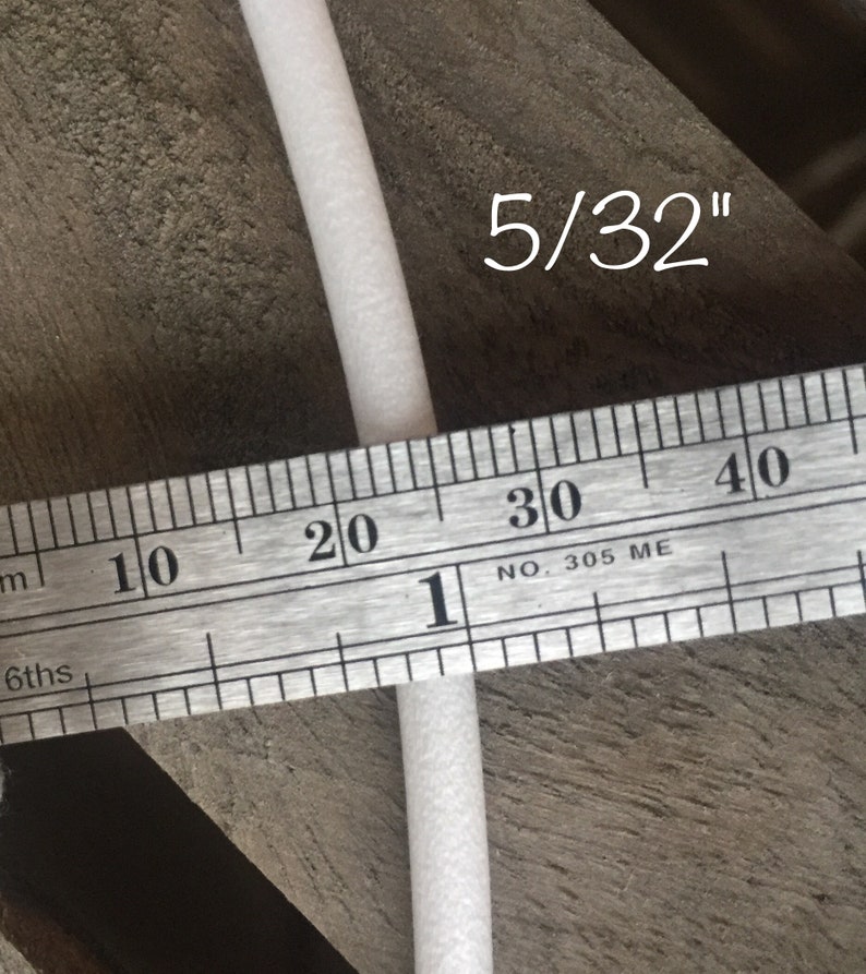 May include: A close-up of a white foam rod, approximately 5/32 inches in diameter, is measured with a metal ruler. The ruler displays both inch and centimeter markings. The text "5/32" is written in white.
