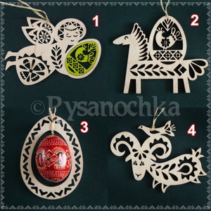 May include: Four wooden ornaments with intricate designs, each featuring a different animal holding a decorated Easter egg. The animals are an angel, a horse, a ram, and a bird. The eggs are decorated with traditional Ukrainian pysanka patterns.