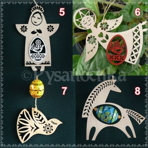 May include: Four wooden ornaments with intricate designs and painted details. Each ornament features a different design: a woman holding an egg, an angel with an egg, a bird with an egg, and a horse with an egg. The ornaments are all white with colorful accents.