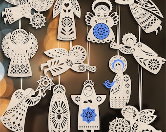 May include: A collection of wooden angel ornaments with intricate cut-out designs. The angels feature various poses and details, including floral and geometric patterns, with some accents of blue. They are suspended by white strings, ideal for holiday decor.