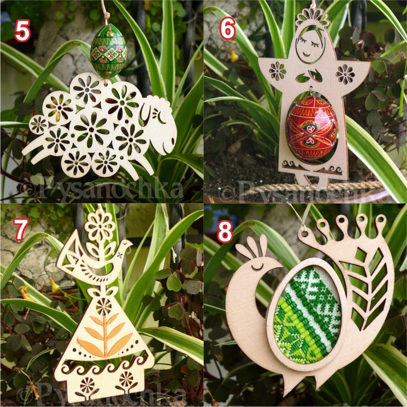 May include: Wooden Easter ornaments in various designs, including a sheep, a figure with an egg, an angel, and a peacock. Each ornament has a unique cutout design and is paired with a decorated egg. The ornaments are hanging in front of green foliage.