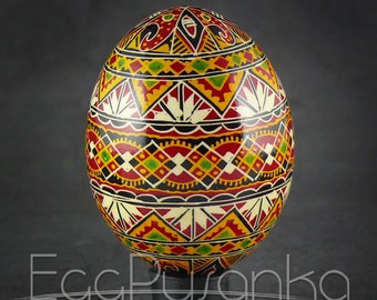 Puede incluir: Un huevo de Pascua ucraniano tradicional, llamado pysanka, decorado con intrincados patrones geométricos en rojo, amarillo, negro y verde.