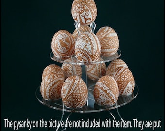 Puede incluir: Un soporte acrílico de tres niveles con 12 huevos marrones decorados con diseños de pysanky blancos. Los pysanky no están incluidos con el soporte.