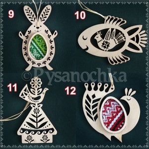 May include: Four wooden ornaments with intricate designs, each featuring a different animal: a bunny, a fish, a bird, and a peacock. Each ornament has a cutout space for a decorative egg with traditional Ukrainian embroidery.