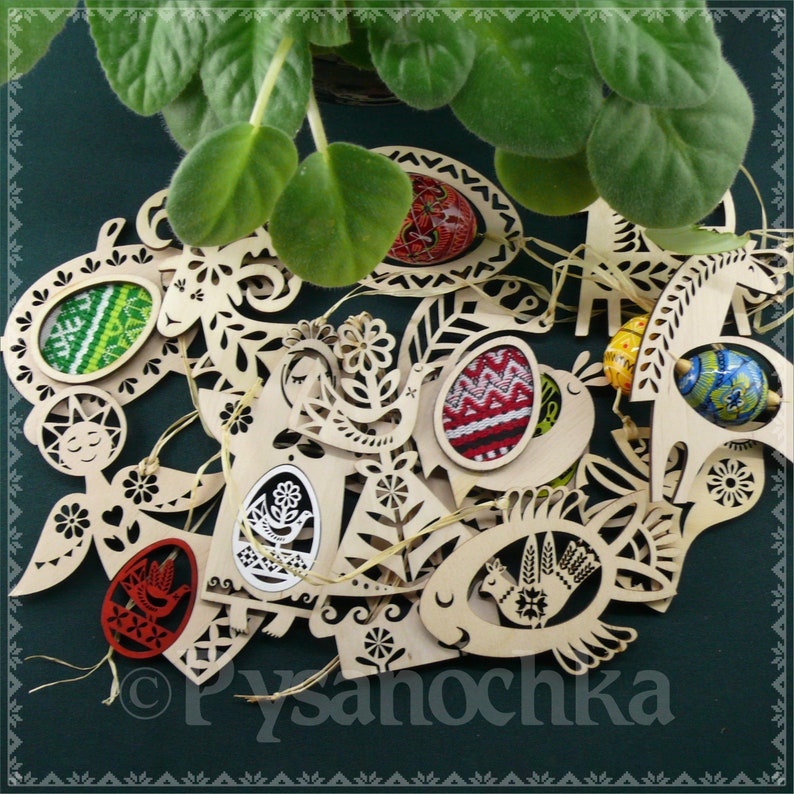 May include: A collection of wooden Easter ornaments featuring intricate designs, including birds, flowers, and eggs. The ornaments are painted in various colors, including red, green, blue, and yellow. The ornaments are arranged on a green background with the text "Pysanochka" visible in the bottom right corner.