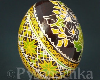 May include: A brown Easter egg decorated with intricate white and yellow floral designs, green leaves, and a geometric pattern in yellow and green.