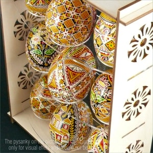 Puede incluir: Un expositor de madera con estantes para guardar huevos de Pascua decorados de forma intrincada. Los huevos est&aacute;n pintados en una variedad de colores y patrones, incluyendo formas geom&eacute;tricas, flores y animales.