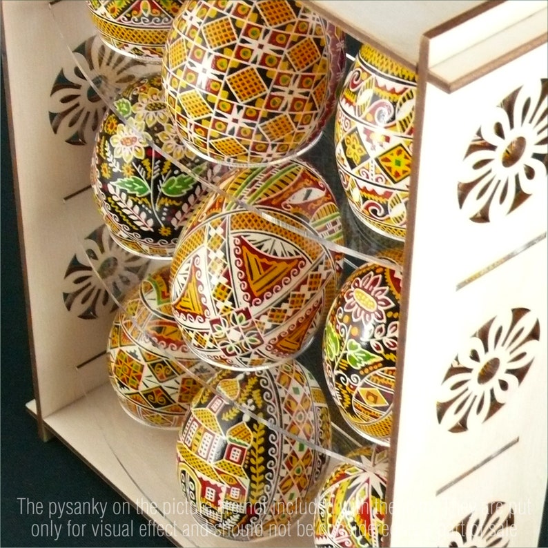 Puede incluir: Un expositor de madera con estantes para guardar huevos de Pascua decorados de forma intrincada. Los huevos est&aacute;n pintados en una variedad de colores y patrones, incluyendo formas geom&eacute;tricas, flores y animales.