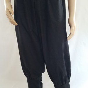 May include: Black pants with a gathered elastic waistband and cuffed legs. The pants are made of a soft, lightweight fabric.
