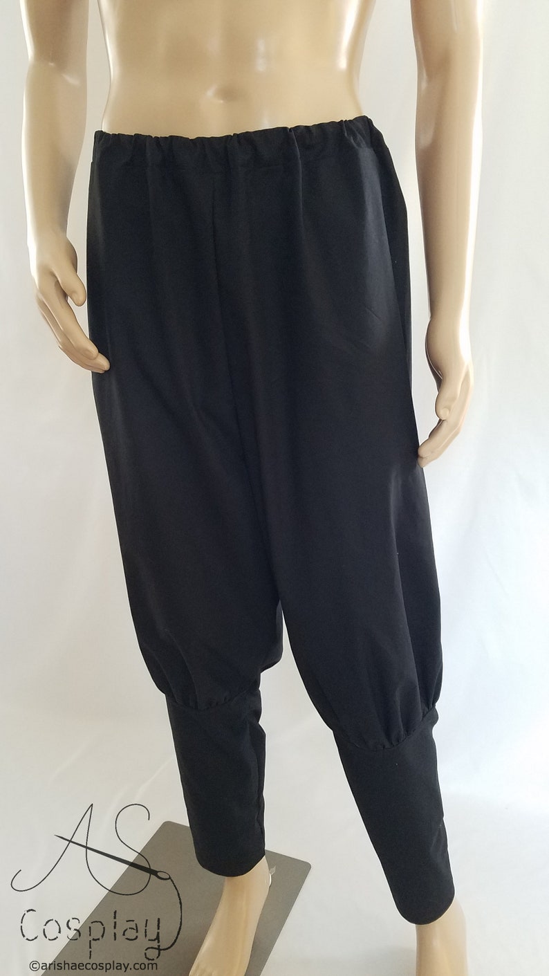 May include: Black pants with a gathered elastic waistband and cuffed legs. The pants are made of a soft, lightweight fabric.