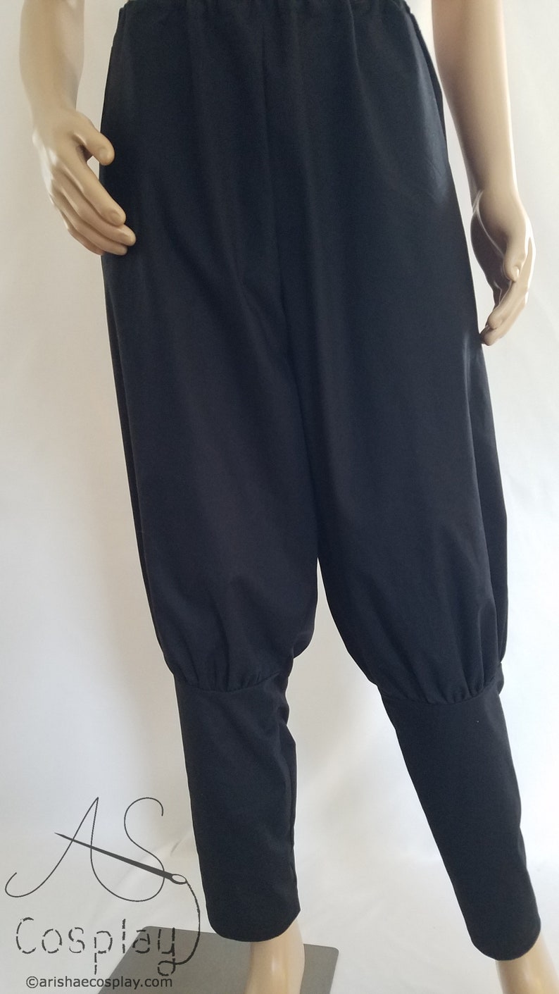 May include: Black cotton pants with a gathered detail at the ankles. The pants have a wide leg and a relaxed fit.
