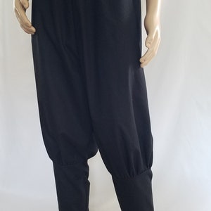 May include: Black pants with a gathered elastic waistband and cuffed legs. The pants are made of a soft, lightweight fabric.