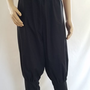 May include: Black pants with a gathered elastic waistband and cuffed legs. The pants are made of a soft, lightweight fabric.