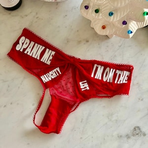 May include: Red lace underwear with the text "SPANK ME NAUGHTY LIST I'M ON THE" printed in white.