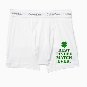 Puede incluir: Bóxer blanco Calvin Klein con un trébol de cuatro hojas verde y el texto "BEST TINDER MATCH EVER."