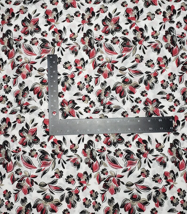 May include: White fabric with a repeating pattern of red, black, and gold floral designs.