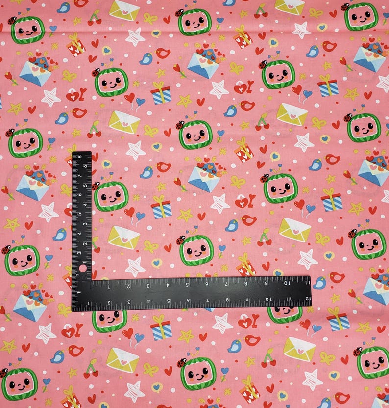 Peut inclure: Tissu rose avec un motif r&eacute;p&eacute;t&eacute; de tranches de past&egrave;que souriantes avec des coccinelles, des enveloppes, des cadeaux, des &eacute;toiles, des coeurs et des oiseaux. Une r&egrave;gle noire est plac&eacute;e sur le tissu. Id&eacute;al pour les loisirs cr&eacute;atifs ou les v&ecirc;tements pour enfants.