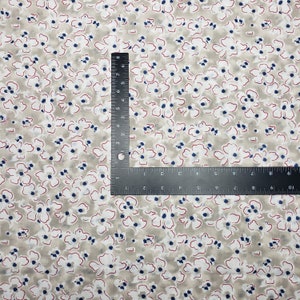 May include: A beige fabric with a white and blue floral pattern. The fabric has a subtle red outline around the flowers.