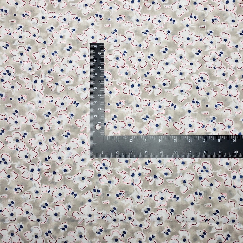 May include: A beige fabric with a white and blue floral pattern. The fabric has a subtle red outline around the flowers.