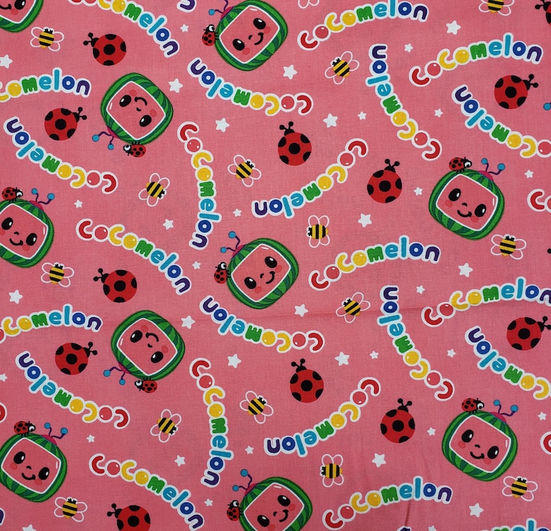 Peut inclure: Tissu rose avec un motif r&eacute;p&eacute;t&eacute; de tranches de past&egrave;que souriantes, de coccinelles, d'abeilles, d'&eacute;toiles et le mot "Cocomelon". Parfait pour les cr&eacute;ations et v&ecirc;tements pour enfants.