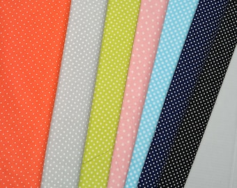 May include: A collection of colorful polka dot fabric swatches. The fabrics include orange, gray, lime green, pink, light blue, navy blue, and black, each with white polka dots. The fabrics are arranged diagonally, showcasing the variety of colors and patterns.