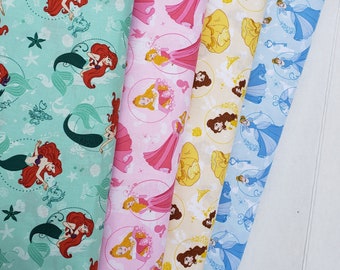 May include: Three fabric panels with different Disney princess designs. The first panel is turquoise with a mermaid pattern. The second panel is pink with a princess pattern. The third panel is yellow with a princess pattern.