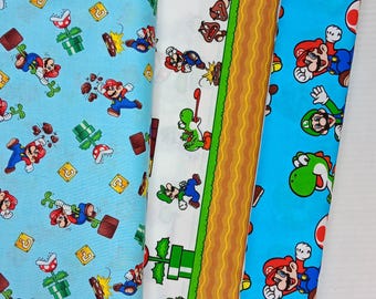 May include: Three vertical strips of fabric featuring video game characters. The left strip is light blue with Mario, green pipes, and question blocks. The centre strip is white with a brown ground border and various characters. The right strip is blue with Mario, Luigi, and green dinosaurs.