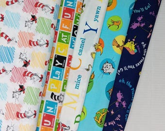 May include: Five strips of cotton fabric featuring Dr. Seuss characters and themes. Patterns include The Cat in the Hat on white, a periodic table style print, alphabet letters with character illustrations, blue circles with various creatures, and dark blue text.