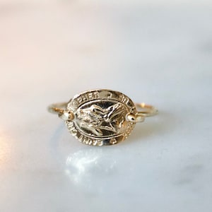 Puede incluir: Anillo de oro con un diseño ovalado que presenta una imagen en relieve de San Cristóbal y el texto "San Cristóbal Protégenos".
