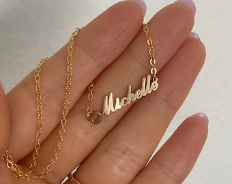 May include: A gold chain necklace with a cursive nameplate pendant that reads "Michelle".
