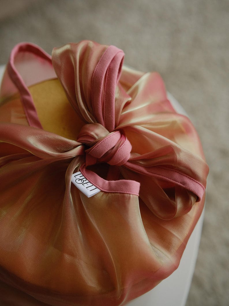 May include: A pink and gold fabric gift wrap with a white tag that says "LIBELLI" on it.