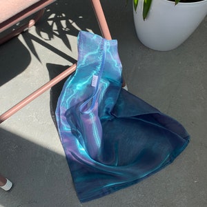 May include: A blue and purple iridescent mesh tote bag with a white tag that says 'LIRA'.