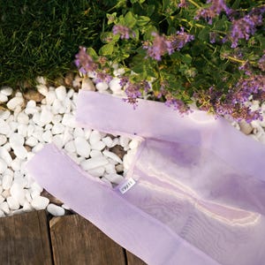 May include: A light purple reusable shopping bag made of mesh fabric with the word "LILLA" printed on the front.