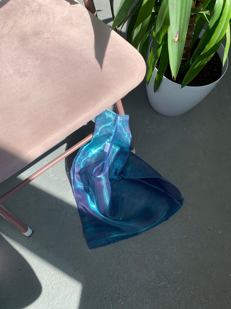 May include: A blue and green iridescent mesh tote bag with a white tag that says 'LILY'.
