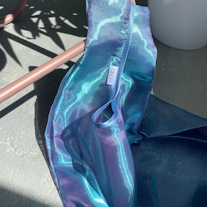 May include: A blue iridescent reusable shopping bag with a white label that says 'IBELLI'.