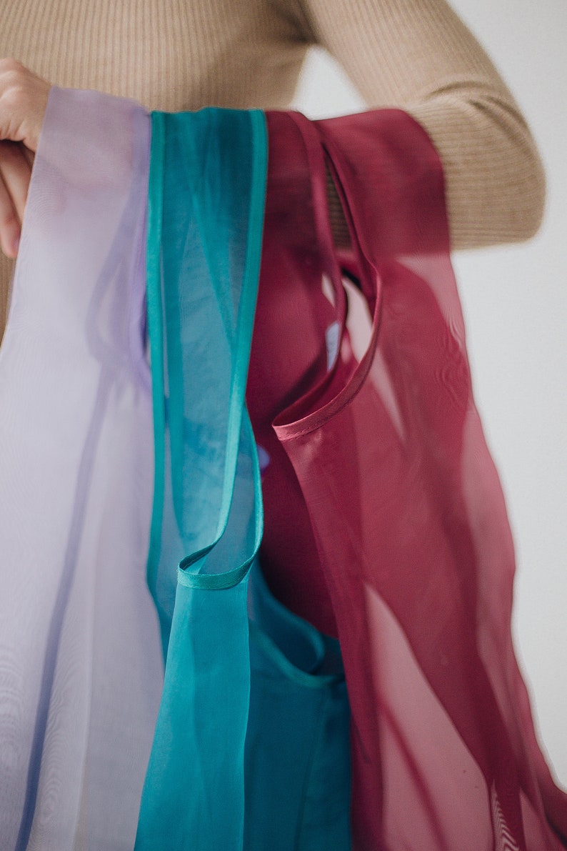 May include: Four sheer fabric scarves in shades of lavender, teal, and burgundy.
