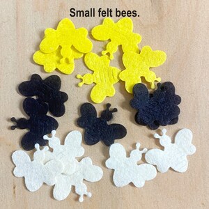 May include: A collection of felt bee shapes in yellow, black, and white. The bees are small and have a simple design.