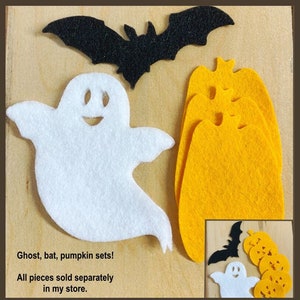 May include: A set of felt Halloween decorations, including a white ghost, a black bat, and a stack of orange pumpkins. The text "Ghost, bat, pumpkin sets! All pieces sold separately in my store." is printed below the decorations.