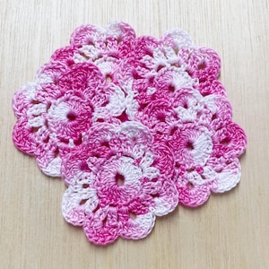 May include: A set of four pink and white crocheted doilies with a flower design.