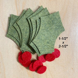 May include: A collection of green felt holly leaf shapes and small red felt circles. The green leaves are layered and measure 1-1/2 inches by 2-1/2 inches. The red circles are scattered at the base of the leaves.