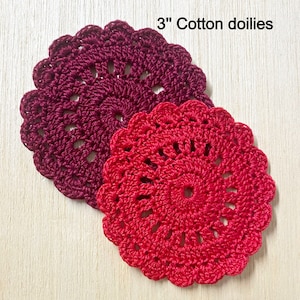 May include: Two 3 inch cotton doilies, one red and one burgundy, with a crocheted design.
