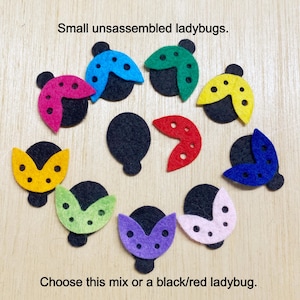 May include: A set of felt ladybug pieces in various colors, including red, yellow, green, blue, purple, and black. The pieces are unassembled and can be used to create a variety of ladybug designs. The text "Small unassembled ladybugs. Choose this mix or a black/red ladybug." is visible in the image.