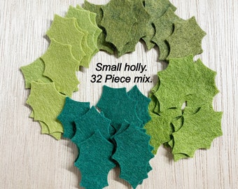 May include: A mix of 32 green felt holly leaves in two shades of green.  The leaves are arranged in a circle on a light wood surface.  Small holly. 32 Piece mix.