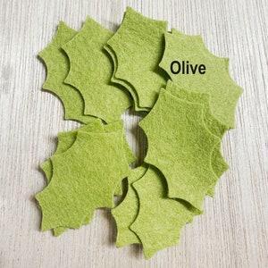Może przedstawiać: Stosik oliwkowych zielonych gwiazdek z filcu. Na jednej z gwiazdek napisano "Olive".